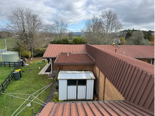 Before: faded red iron roof on a brick home